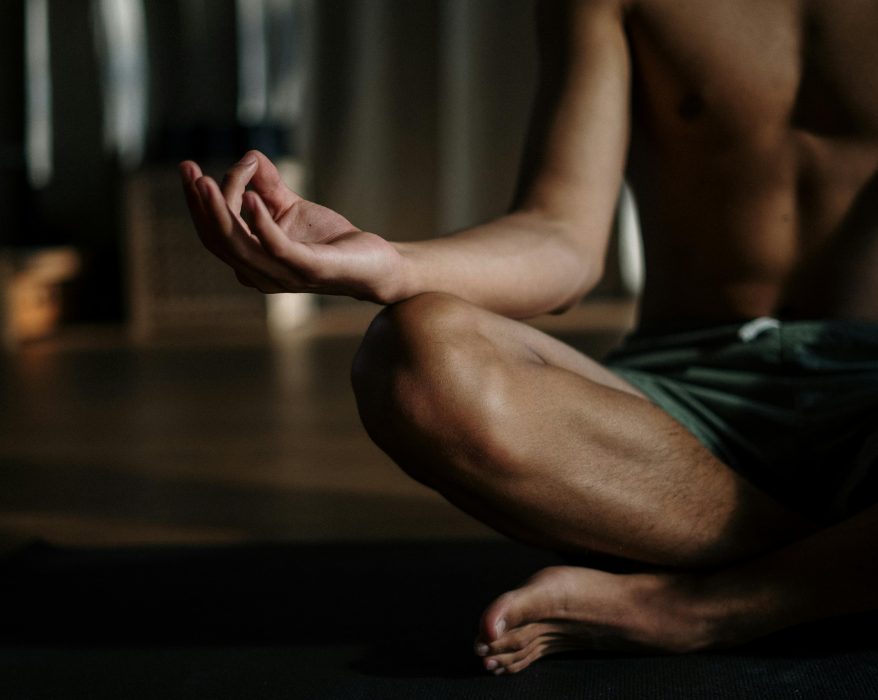 Close-up of a person meditating in a yoga pose with their hand in a mudra gesture.